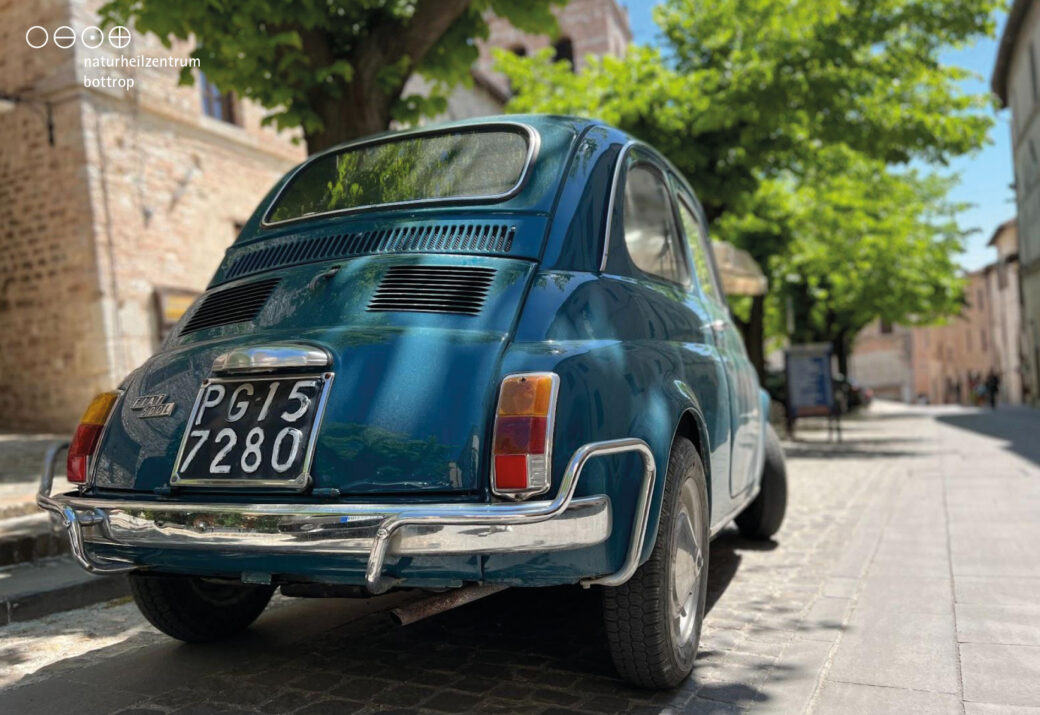 Parkender blauer Fiat 500 in Städtchen