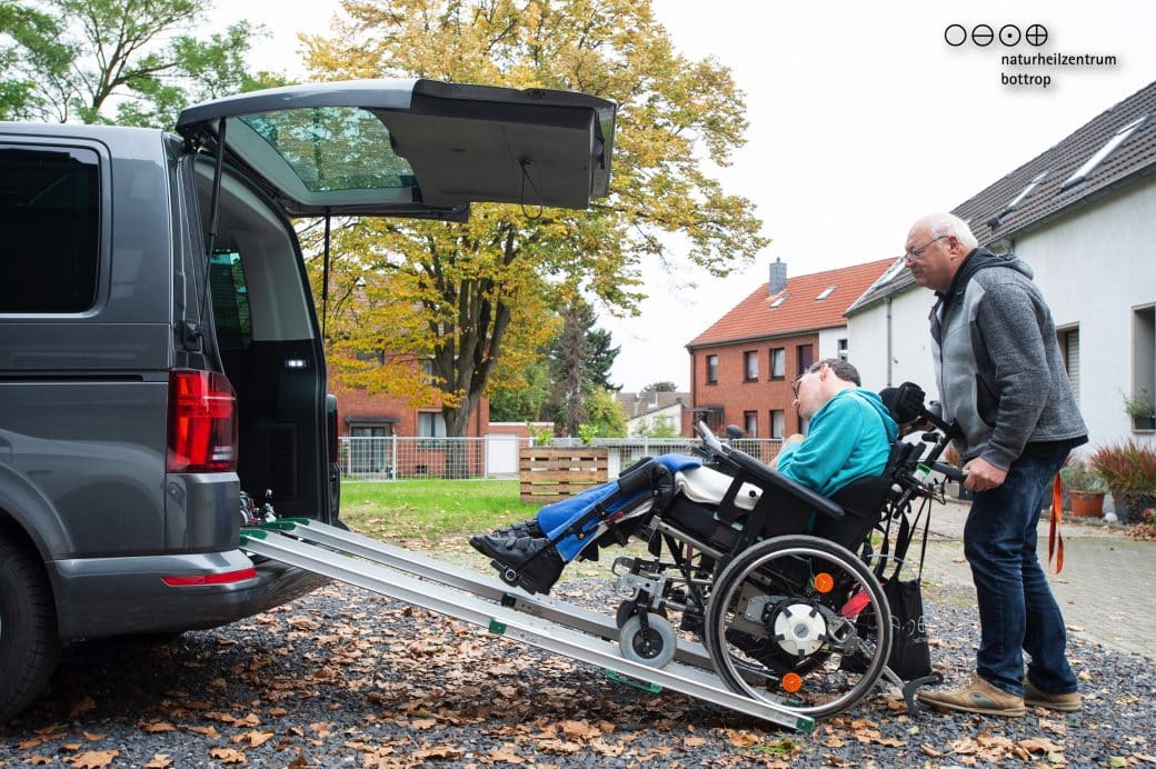 André Vogel est poussé dans la camionnette par son père en fauteuil roulant