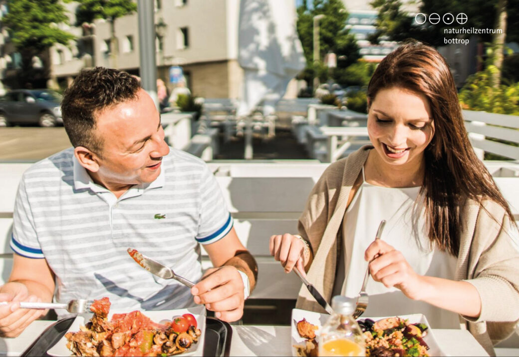 A man and a woman eating on a restaurant terrace