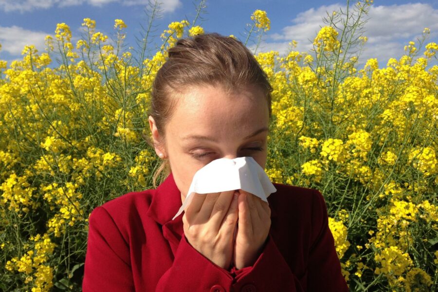 Young woman blowing her nose in canola field