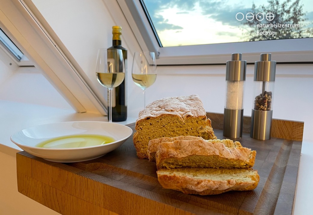 Ein aufgeschnittenes Brot mit Olivenöl auf einer Holzplatte