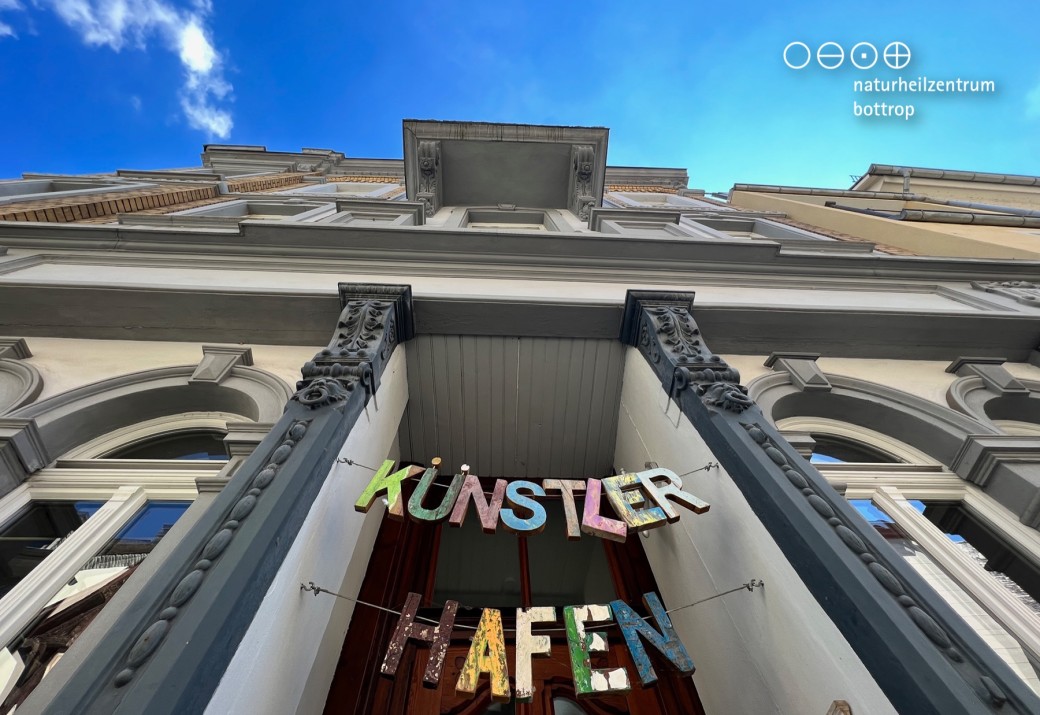 View from below of a house facade and front door, on which is written artist port